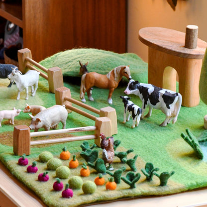 Toy farm set with animals and a garden on a green felt background