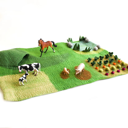 Toy farm set with animals and vegetables on a green fabric background