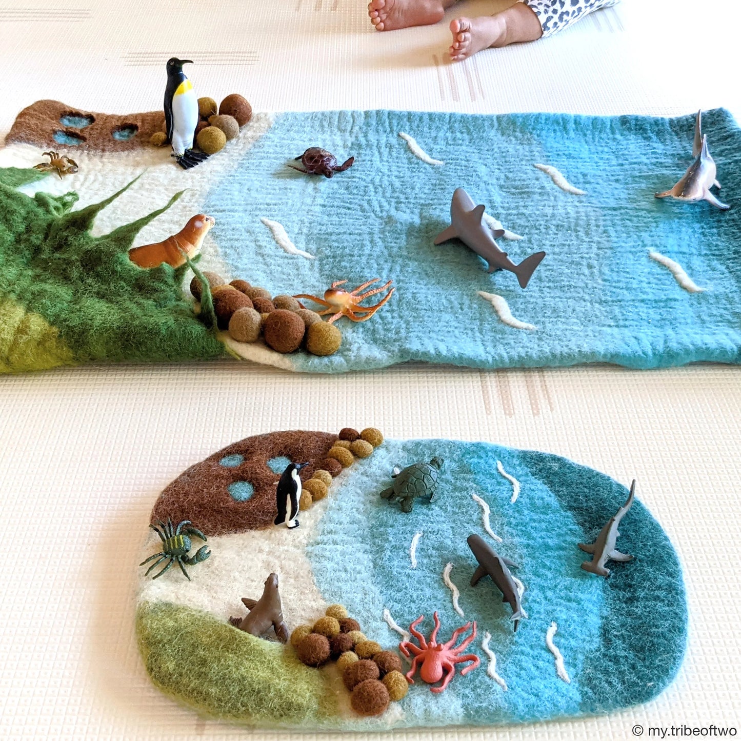 Felt play mat with ocean-themed animals and landscape on a light surface.