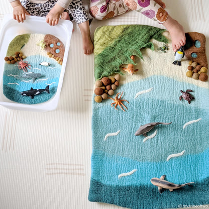 Children playing with a felt ocean scene on a blanket