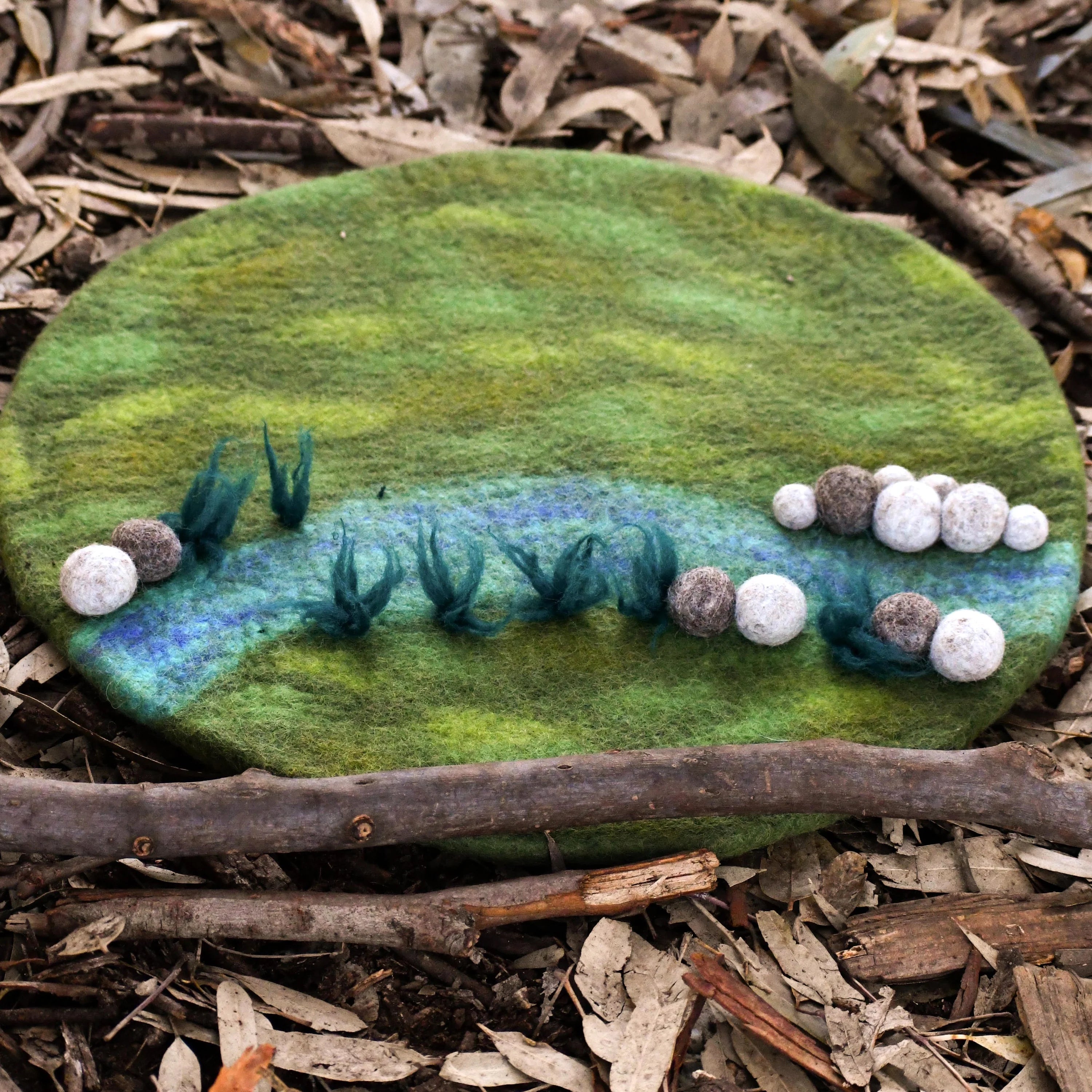 Felted stone with a landscape design on a natural background
