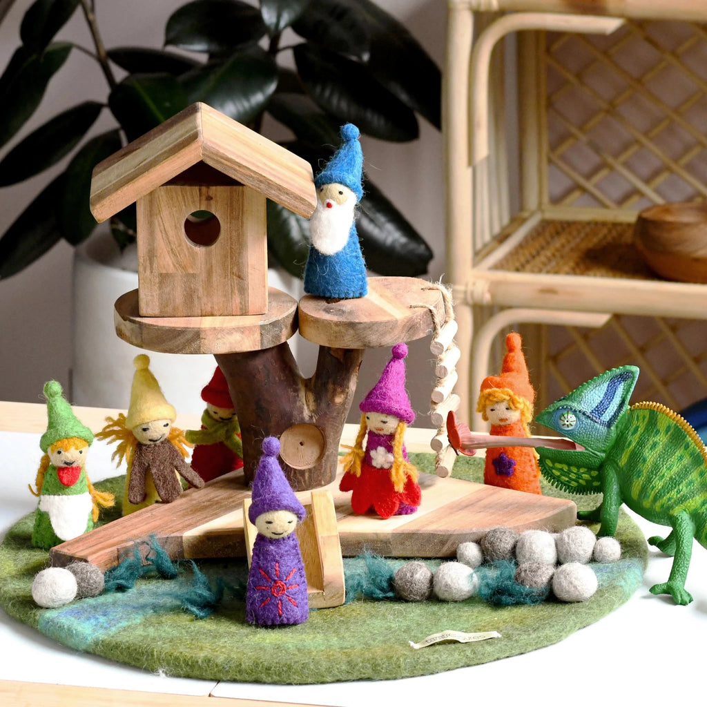 Wooden gnome village with a treehouse and various gnomes around, set against a blurred indoor background.