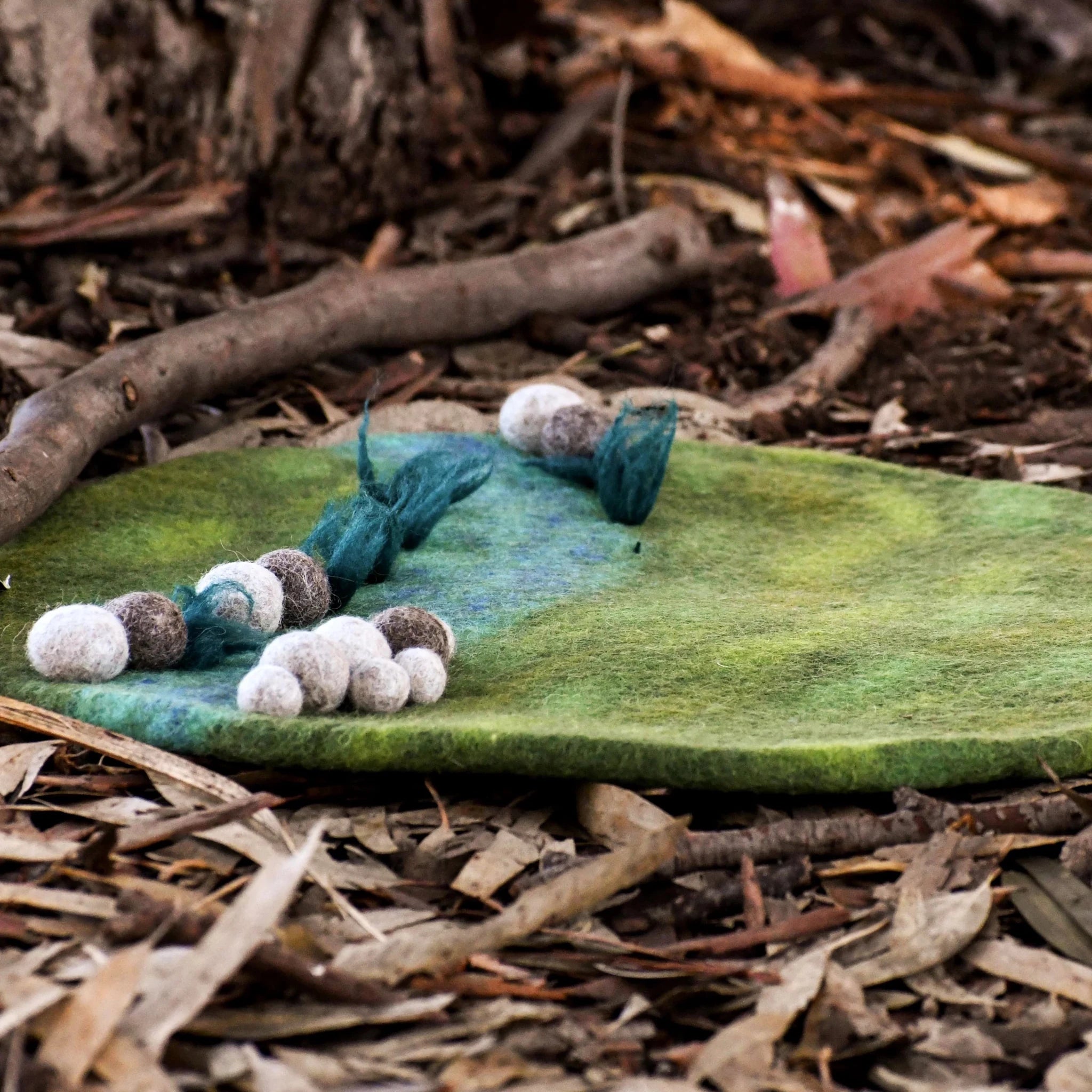 Felted creature on a green stone with natural background