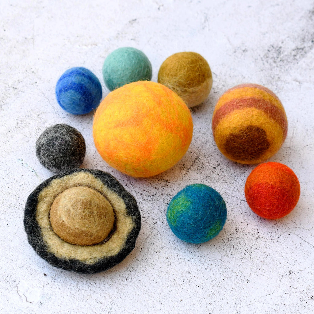 Colorful felted wool balls resembling planets on a textured white surface