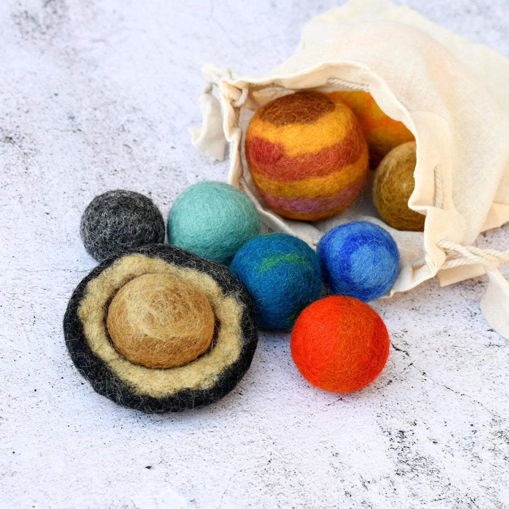 Colorful felted balls with a drawstring bag on a textured surface