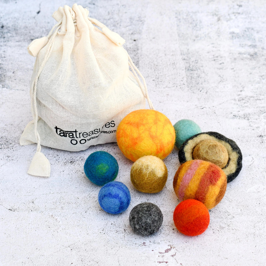 Colorful felted wool balls resembling planets on a textured surface with a drawstring bag.