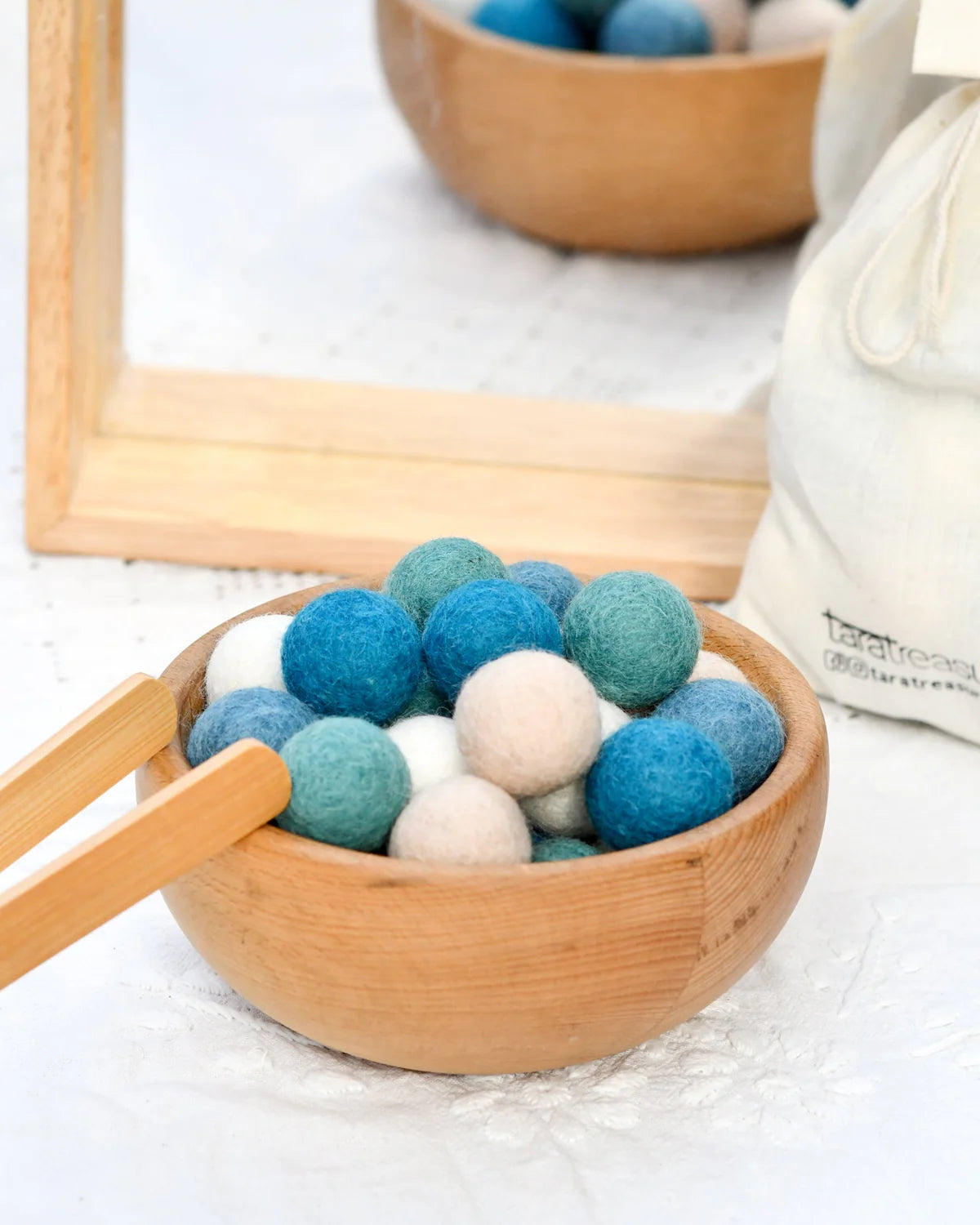 Bowl filled with blue and white felt balls on a light surface.