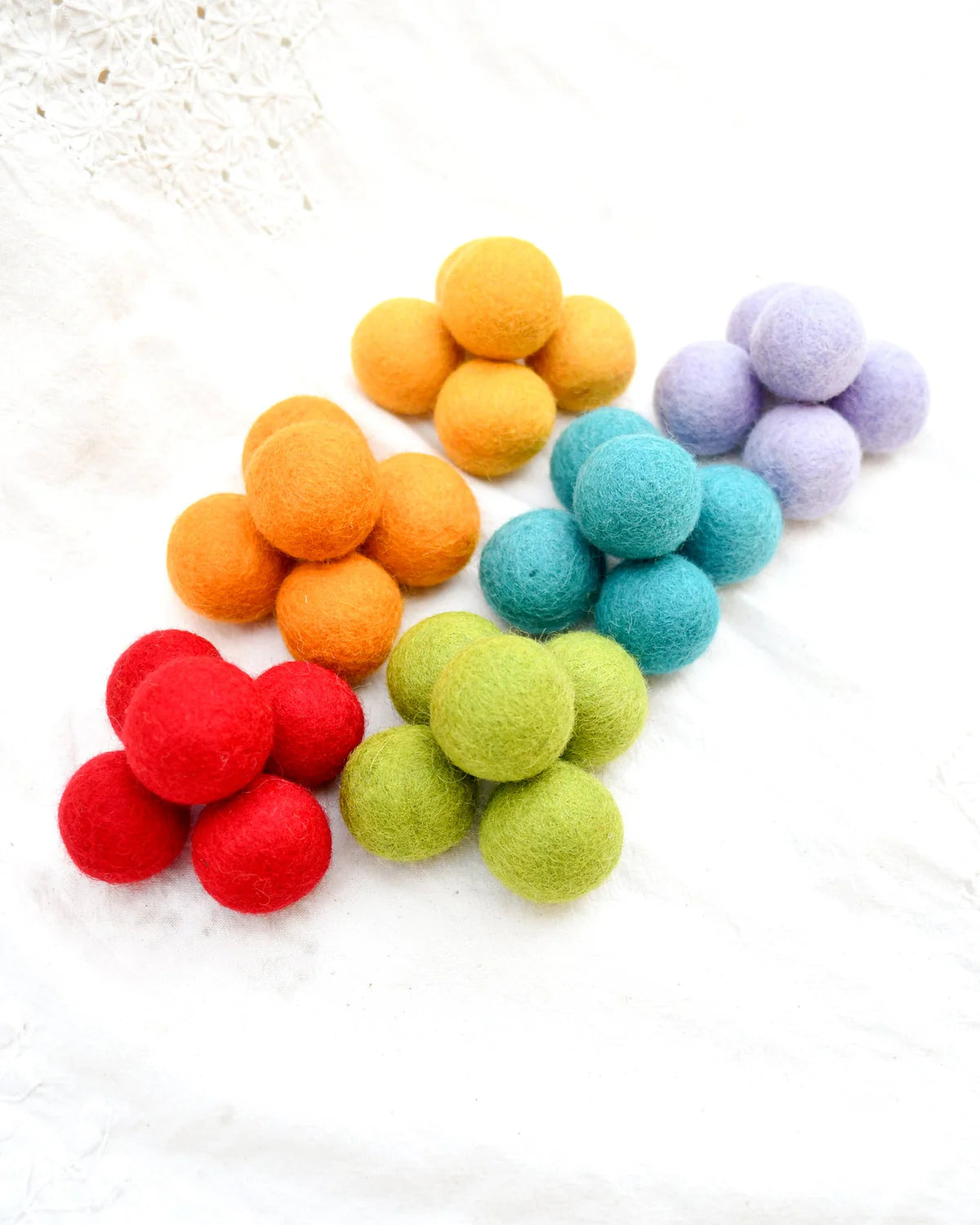 Colorful felt balls arranged in a pattern on a white surface