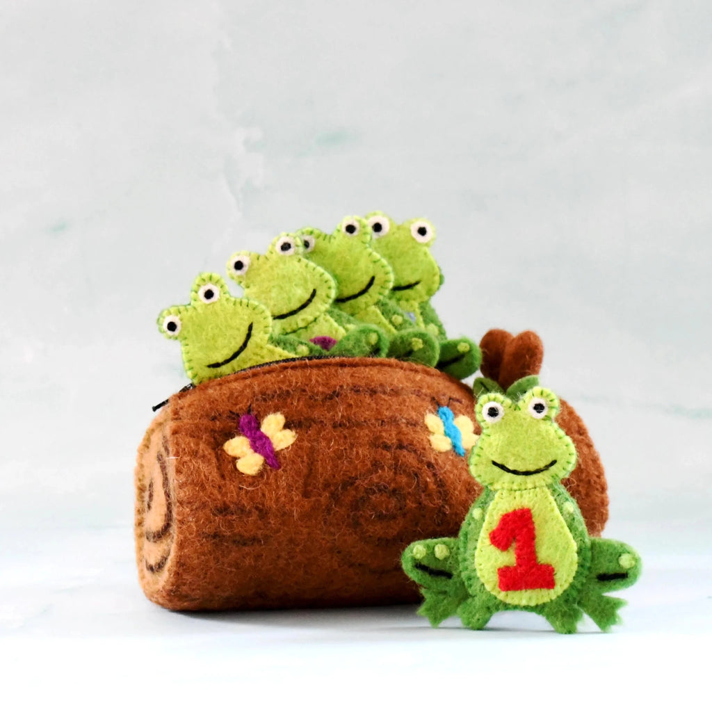 A brown felt log-shaped pouch with embroidered flowers, green felt frog characters sitting inside, and one larger green felt frog with a red number 1 on the front, set against a light gray background.