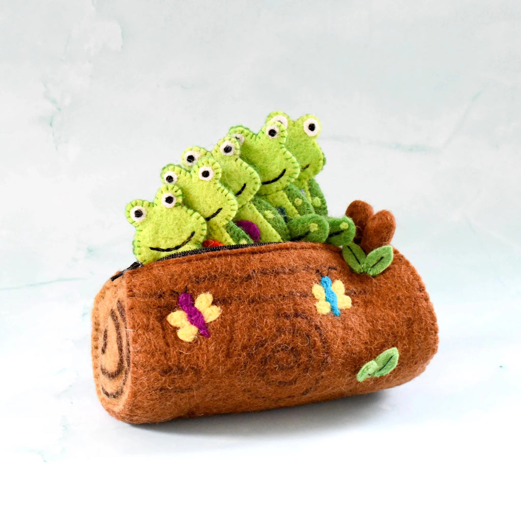 Plush toy with green frogs on a brown log against a light background