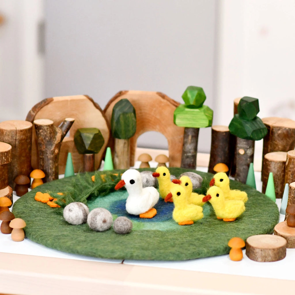Wooden toy set with ducks and trees on a felt surface