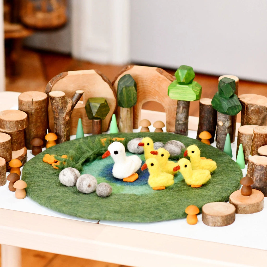 Wooden toy set with ducks and a pond on a felt surface
