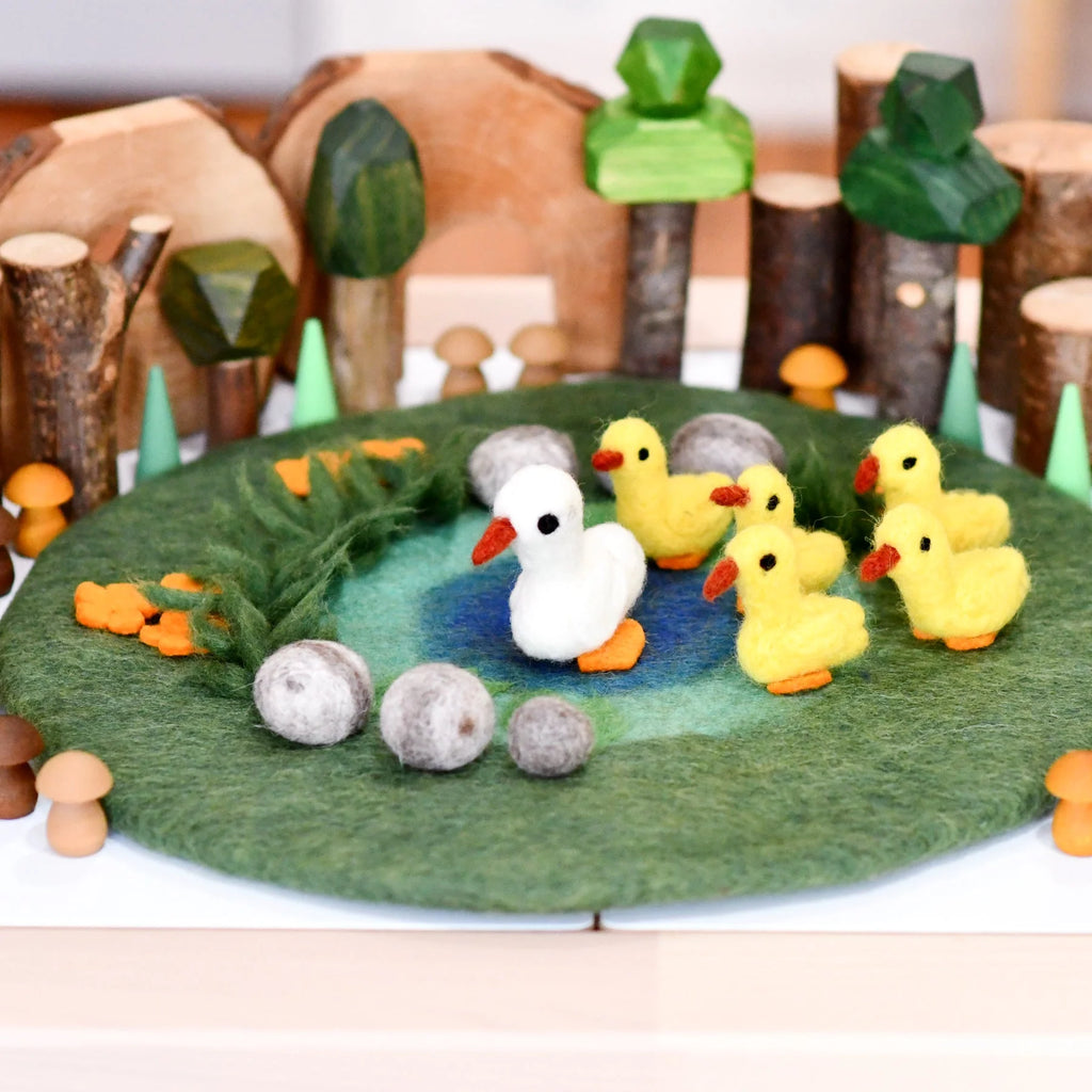Felt playset with ducks and trees on a green felt surface
