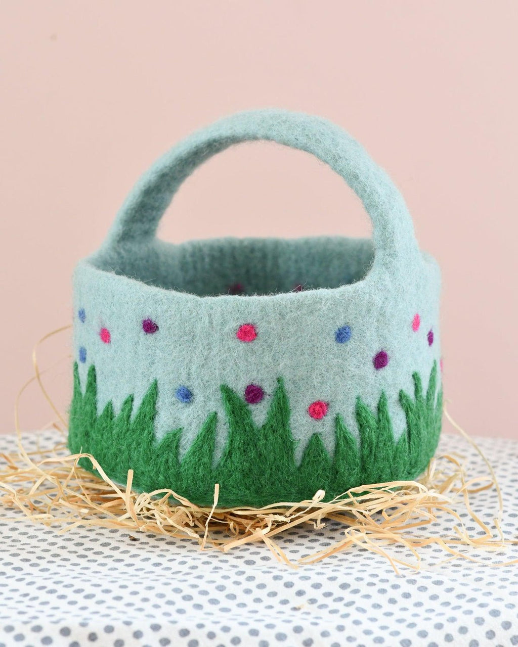 Felted basket with embroidered flowers and grass on a polka dot surface