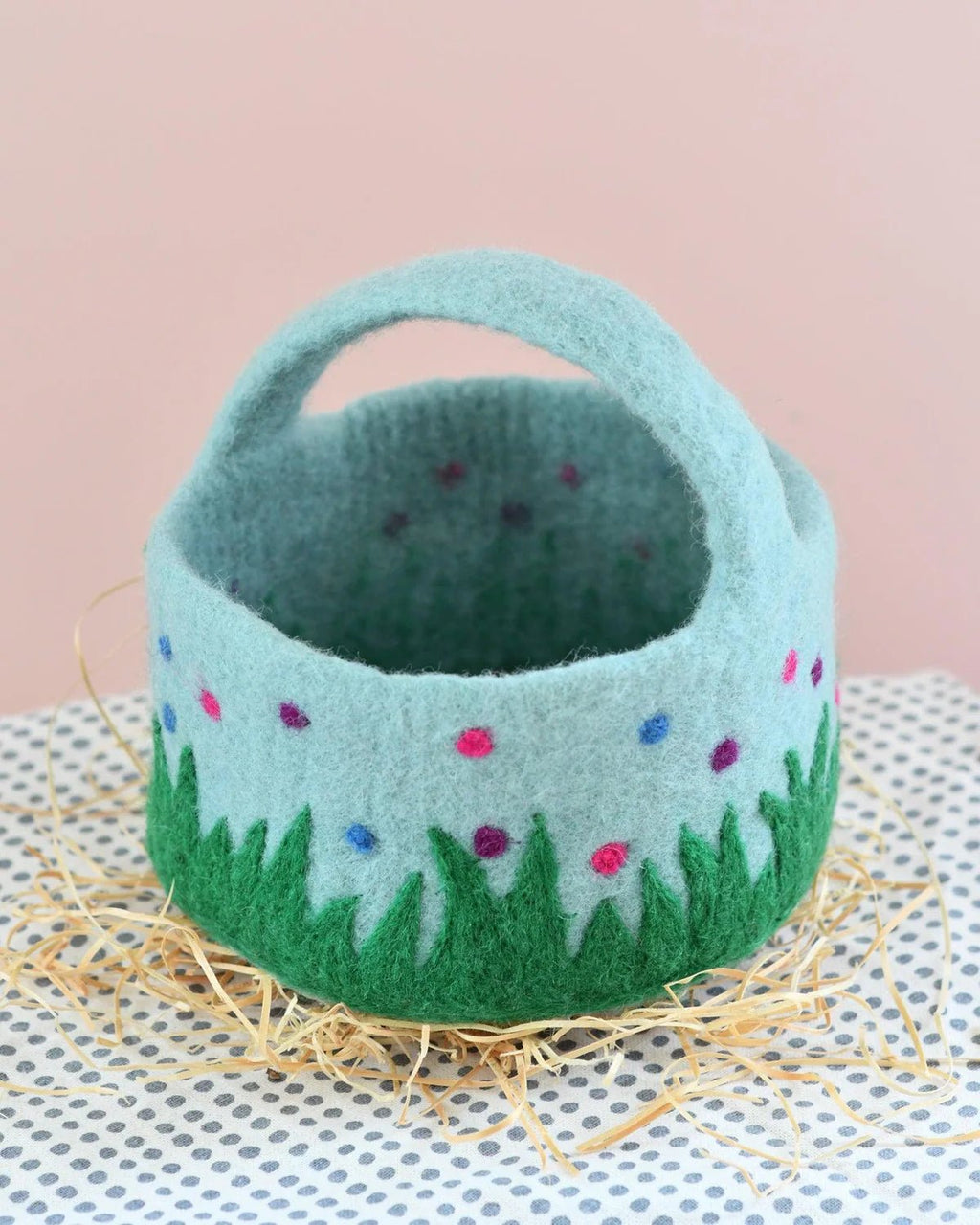 Felted basket with floral design on a textured surface