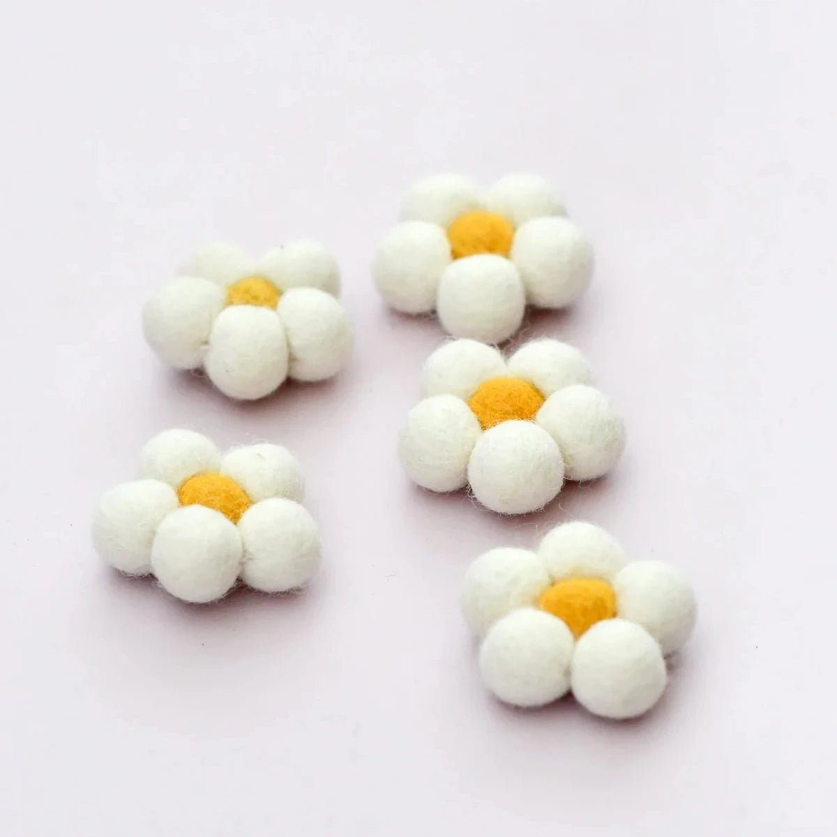 White flower-shaped candies with yellow centers on a light pink background