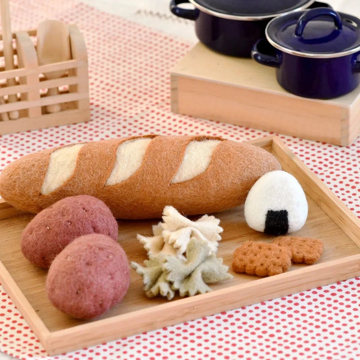 Wooden tray with bread, potatoes, and cookies on a red and white checkered tablecloth.