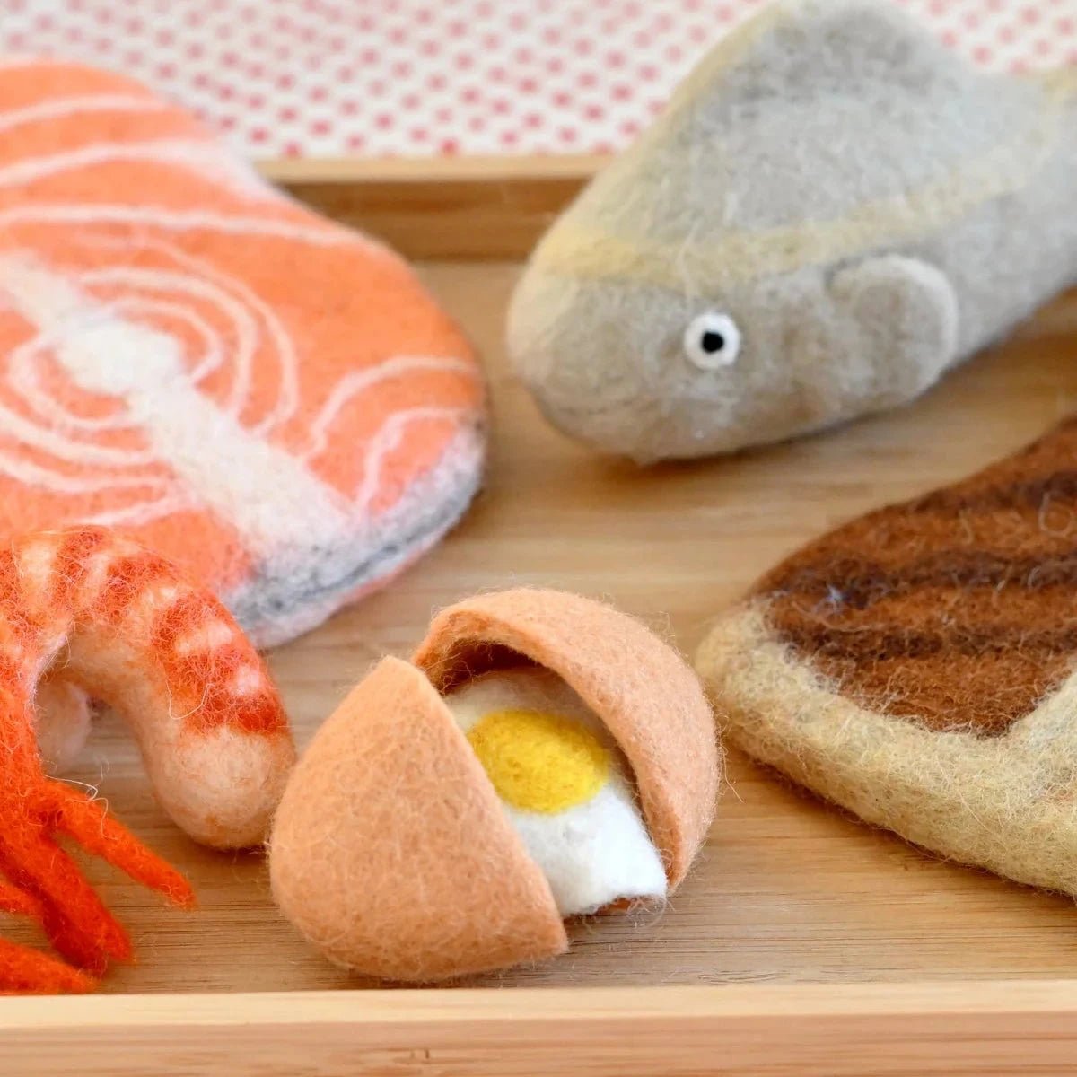 Toy sushi set on a wooden board with a polka dot background
