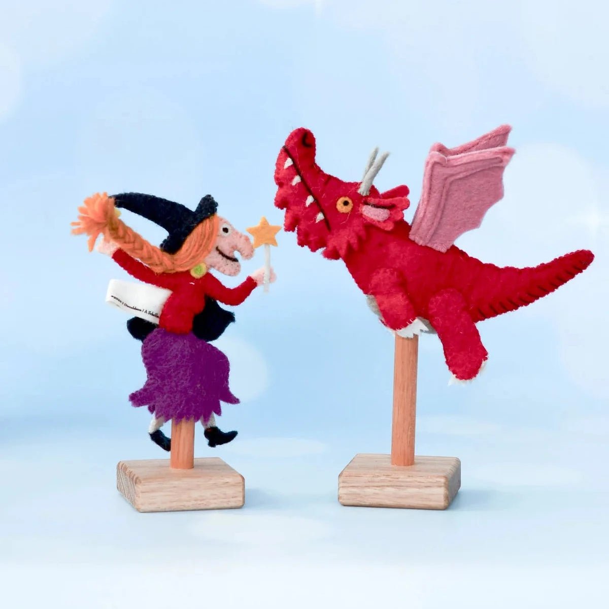 Decorative figure of a witch and red dragon on stands against a light blue background