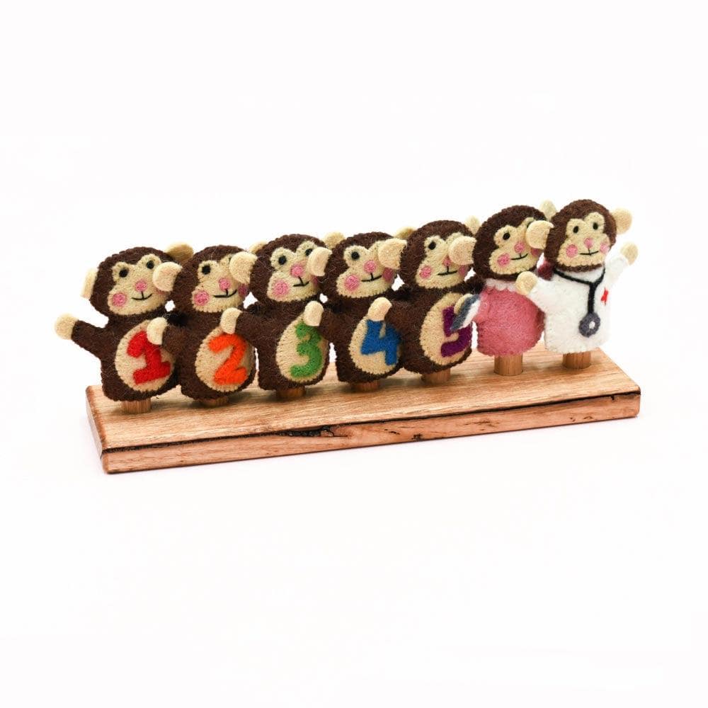 Set of seven monkey figurines with colorful numbers on a wooden stand against a white background