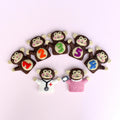 Set of monkey-shaped finger puppets with numbers and letters on a light pink background