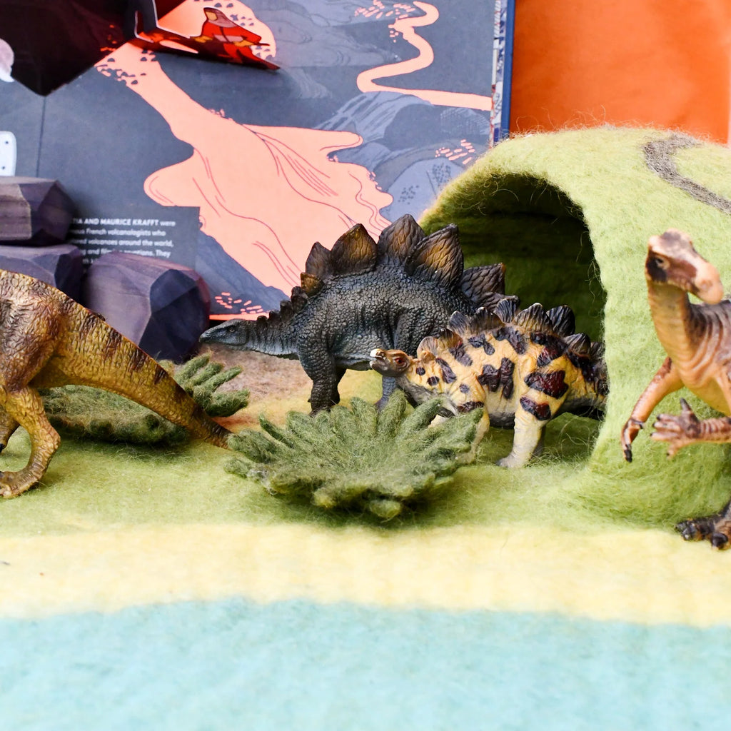 Toy dinosaurs on a felt play mat with a colorful background