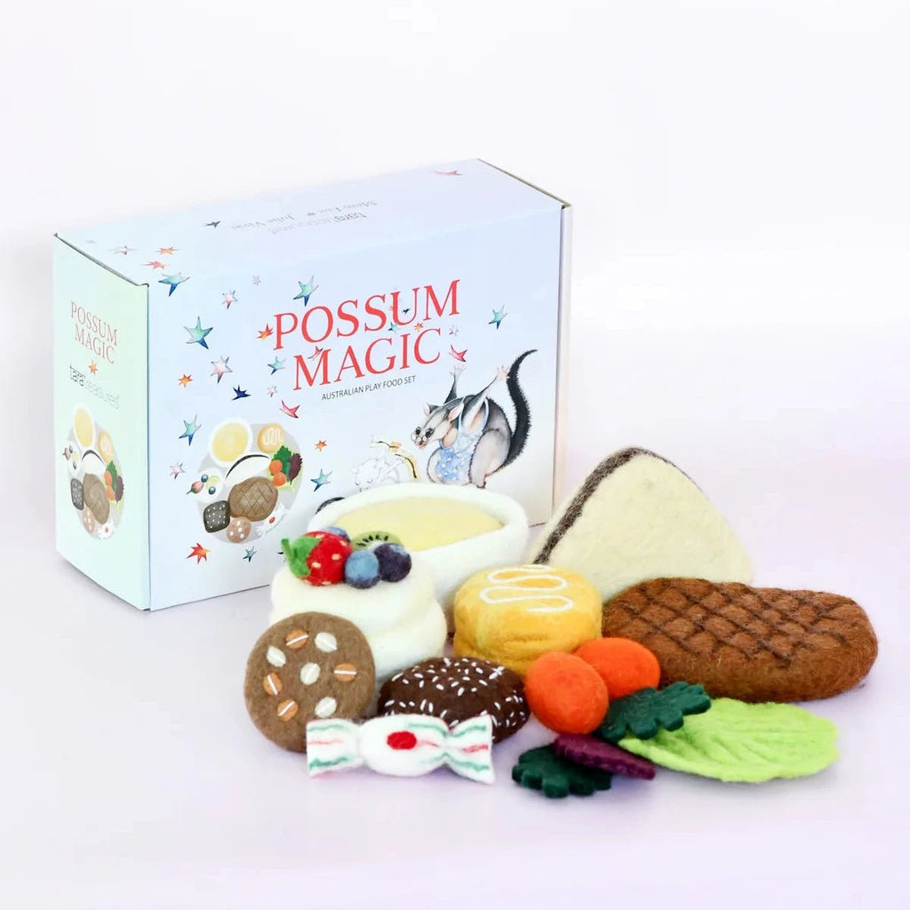 A toy food play set with felt vegetables, cakes, cookies, and a small bowl, arranged in front of a light blue box printed with 'Possum Magic' and an illustration of a possum.