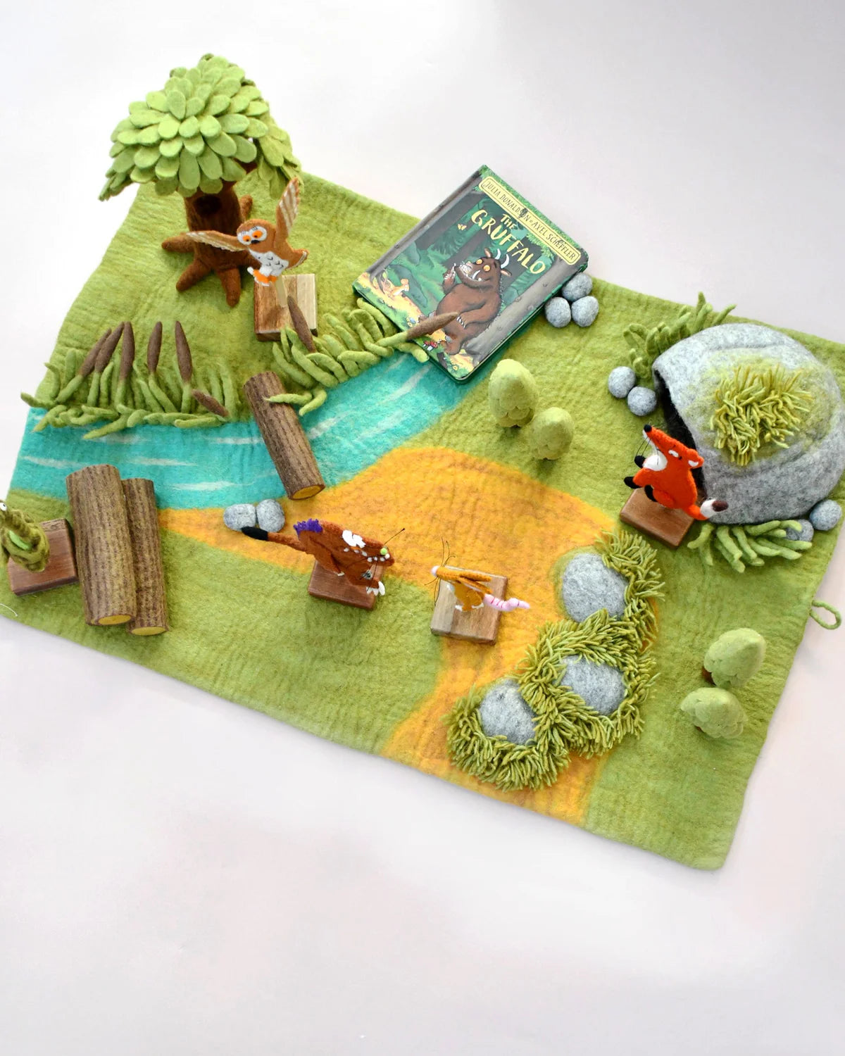 Felt play mat with animal figures and a book on a white background