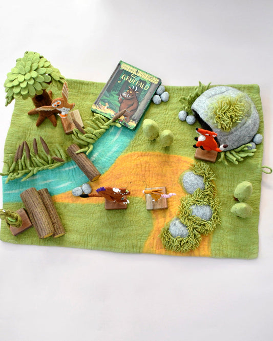 Felt play mat with forest scene and book on a white background