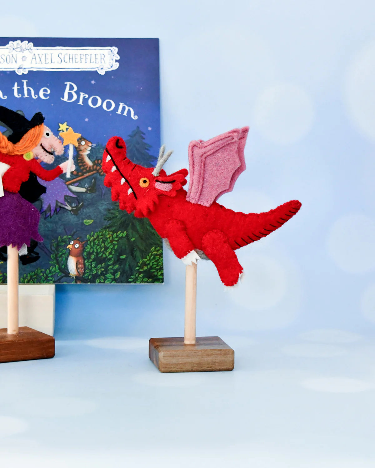 Red dragon puppet on a stand with a children's book titled 'On the Broom' in the background.