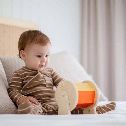 Baby sitting on a bed holding a colorful toy