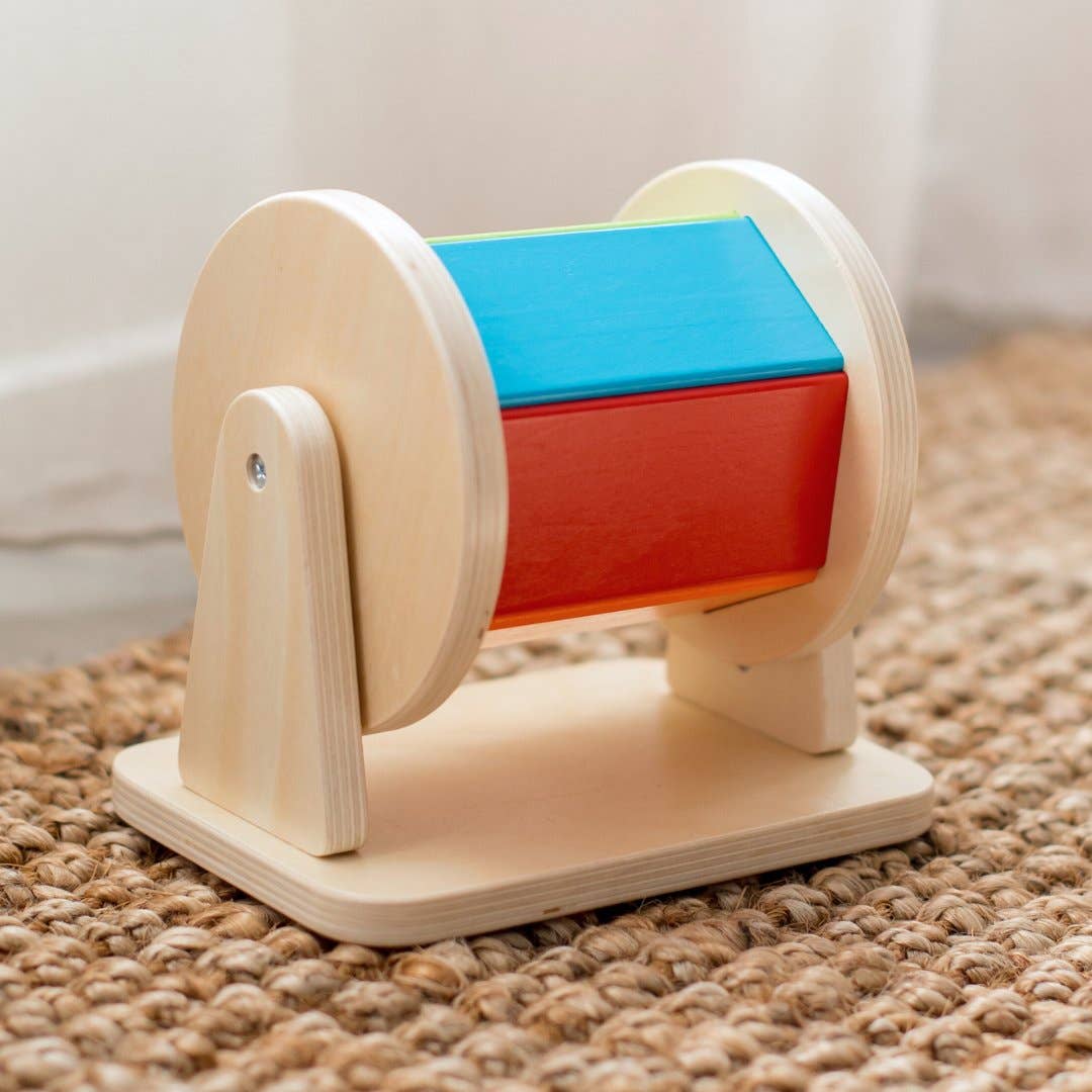 Wooden toy with colorful cylindrical sections on a textured surface