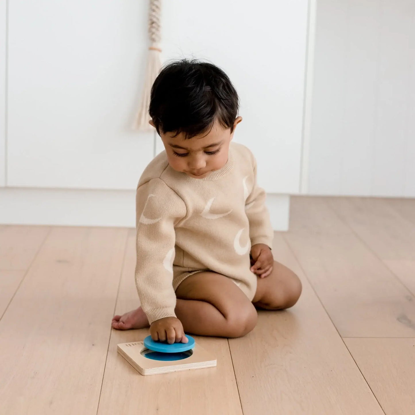 Child playing with a toy on a wooden floor
