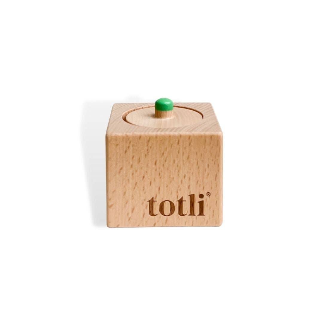 Wooden block with a green knob on top, branded 'totli', on a white background