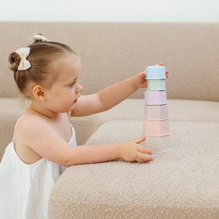 Child playing with colorful stacking toys on a beige couch