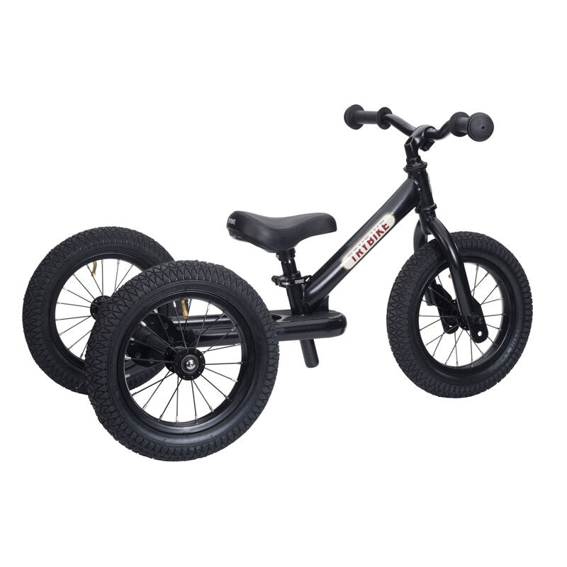 Black balance bike with training wheels on a white background