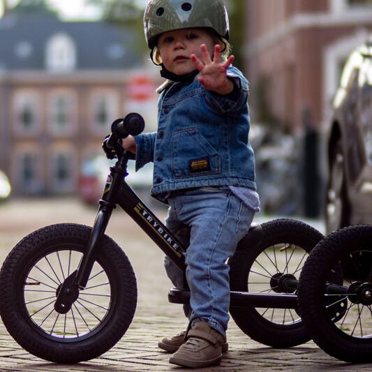 Child on a balance bike wearing a helmet in an urban setting