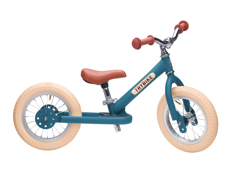 Children's balance bike with teal frame and wooden wheels on a white background