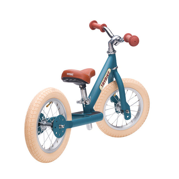 Children's balance bike with teal frame and beige tires on a white background