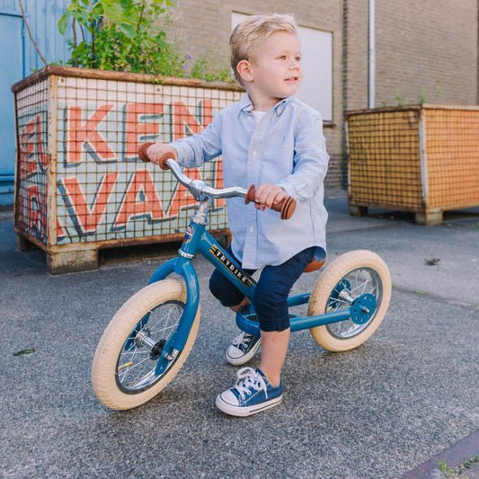 Child on a balance bike in an urban setting with colorful crates in the background