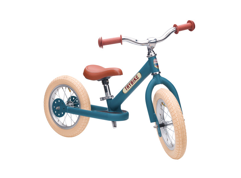 Children's balance bike with teal frame and brown seat on a white background