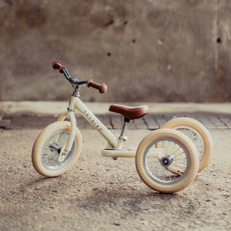 Children's balance bike with training wheels on a concrete surface