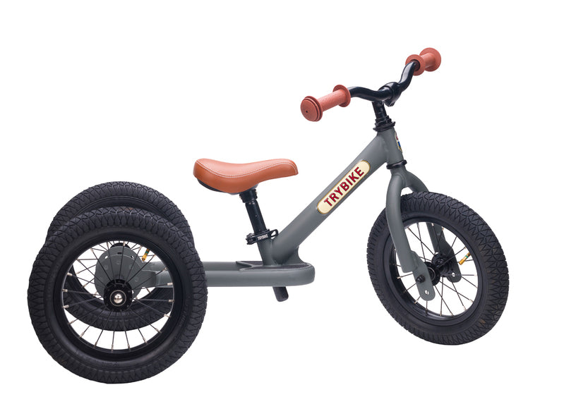 Gray balance bike with brown handlebar and seat on a white background