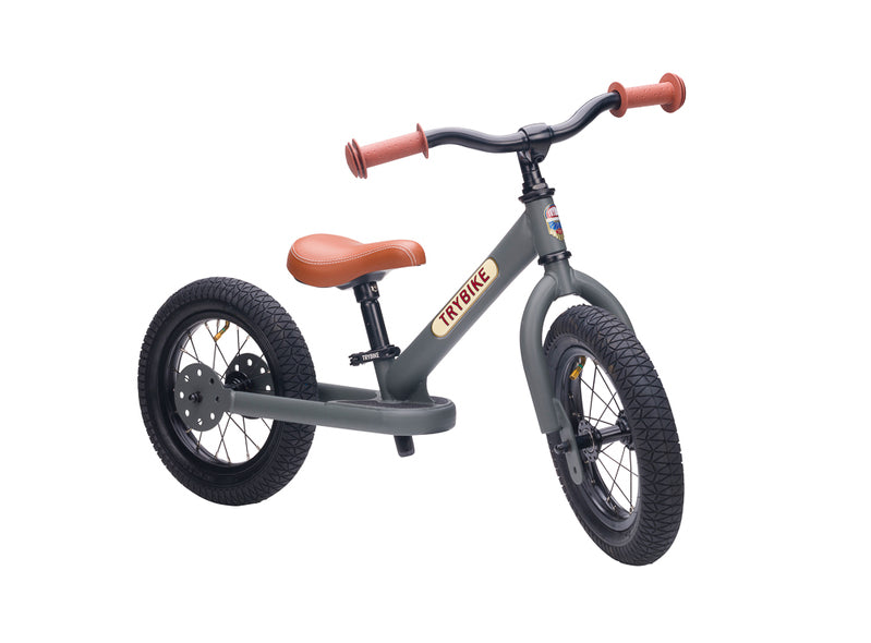 Children's balance bike with gray frame and brown seat on a white background