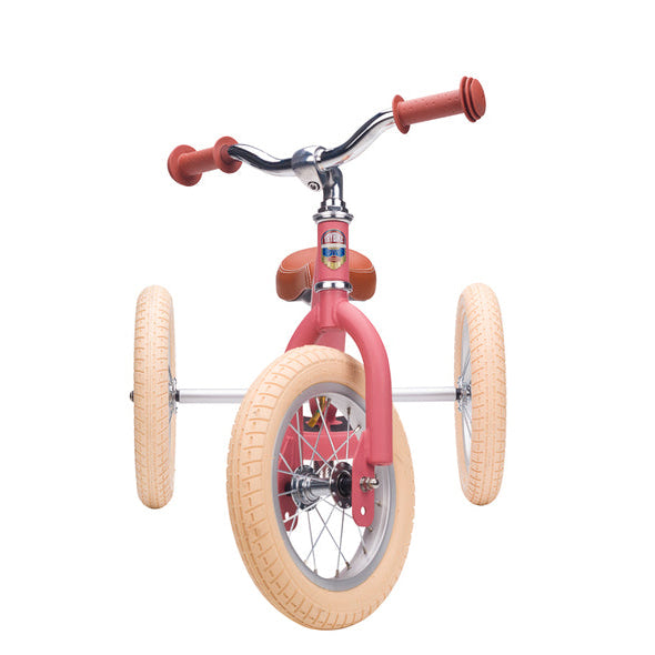 Pink balance bike with tan wheels on a white background