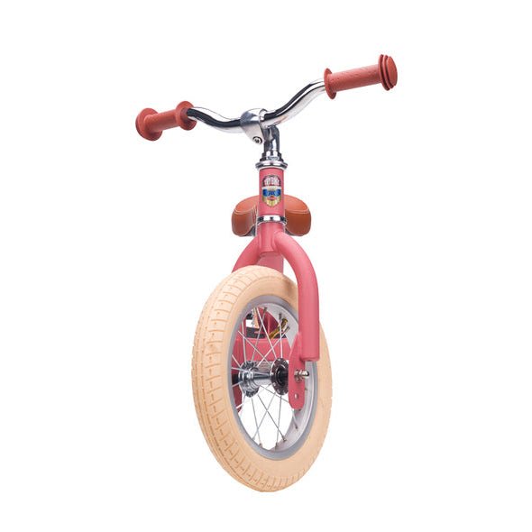 Pink balance bike with beige tire on a white background