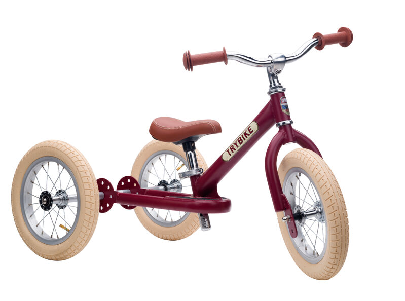 Red balance bike with beige tyres on a white background