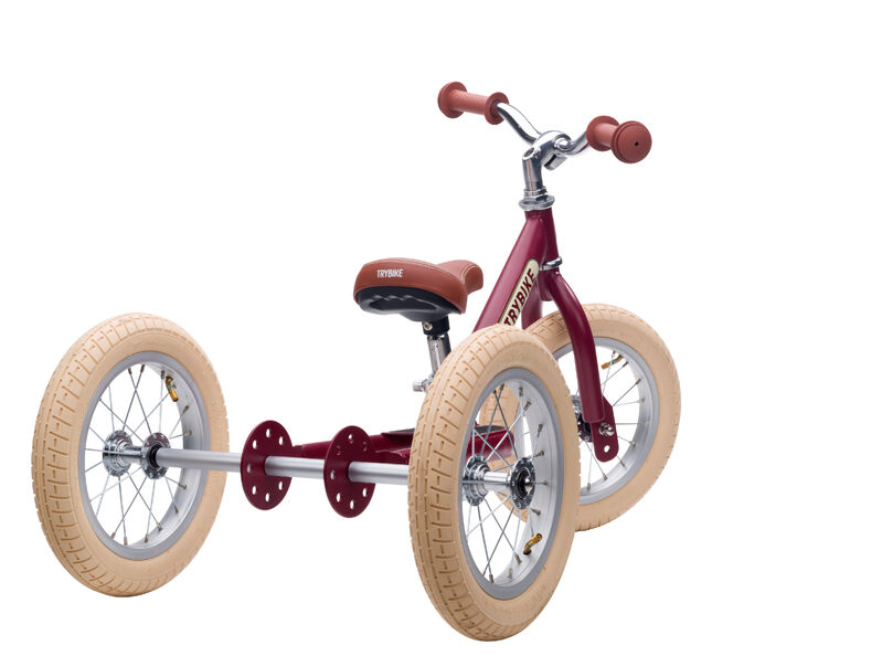 Red balance bike with beige tyres on a white background