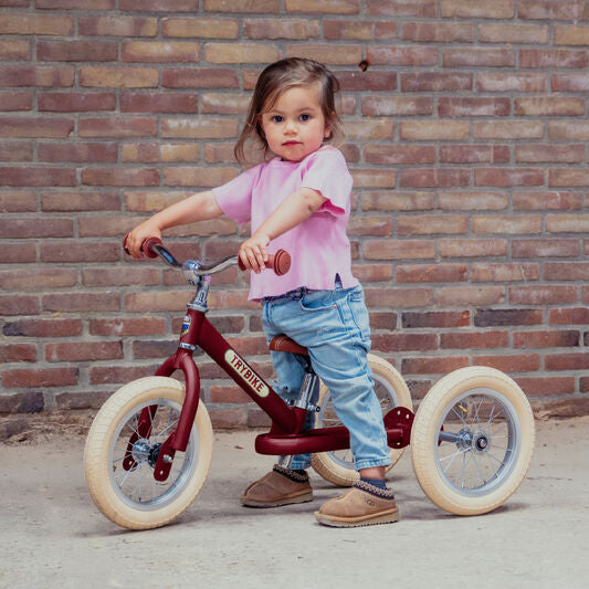 Child on a tricycle in front of a brick wall