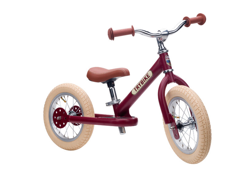 Red balance bike with beige tires on a white background